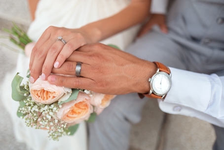 newlyweds holding hands on bouquet